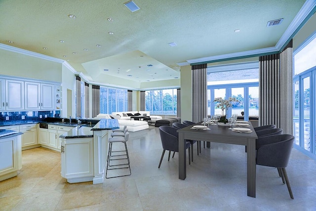 kitchen featuring dark stone counters, white cabinets, a kitchen breakfast bar, backsplash, and french doors