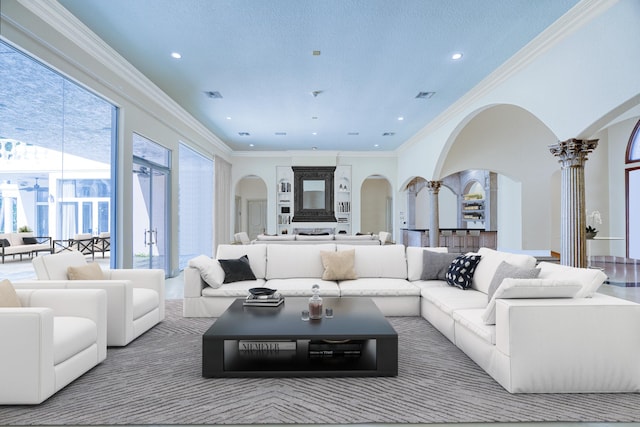 living room featuring a textured ceiling, crown molding, and ornate columns