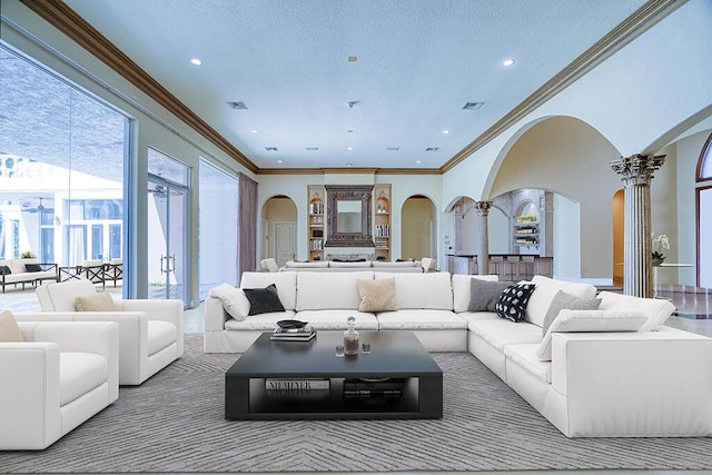 living room with a textured ceiling, a healthy amount of sunlight, decorative columns, and ornamental molding