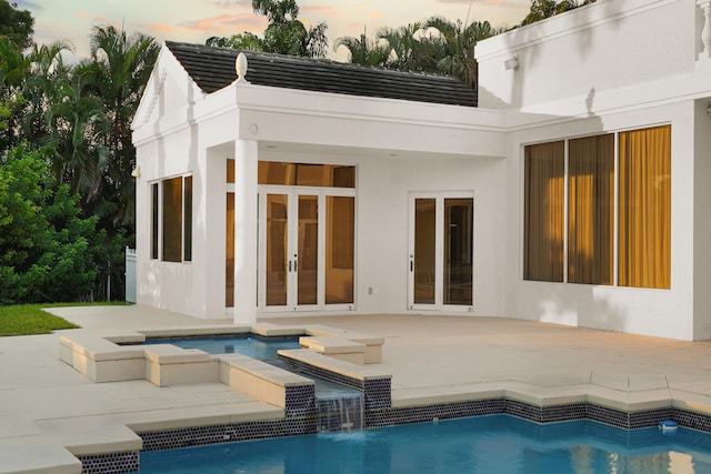 pool at dusk featuring a patio and pool water feature