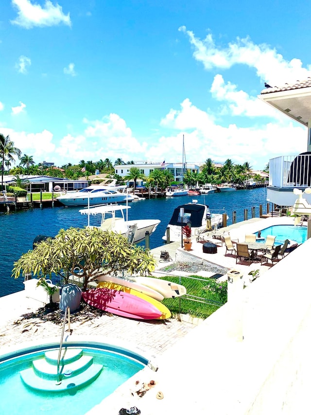 view of swimming pool with a water view, a dock, and a patio