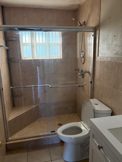 bathroom featuring vanity, tile patterned floors, walk in shower, and tile walls