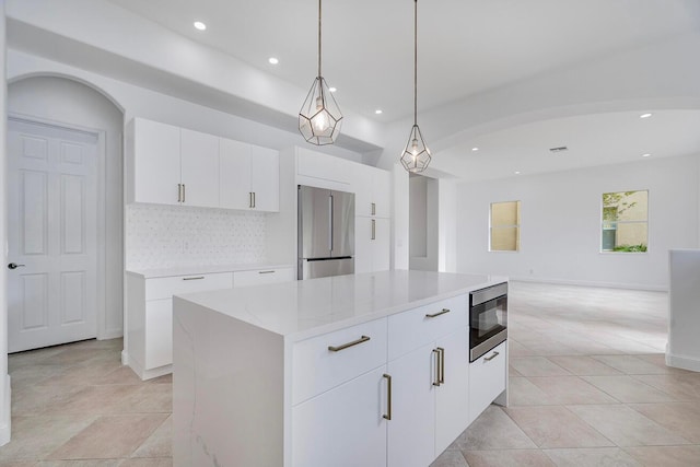 kitchen featuring a kitchen island, stainless steel appliances, light tile flooring, tasteful backsplash, and white cabinetry