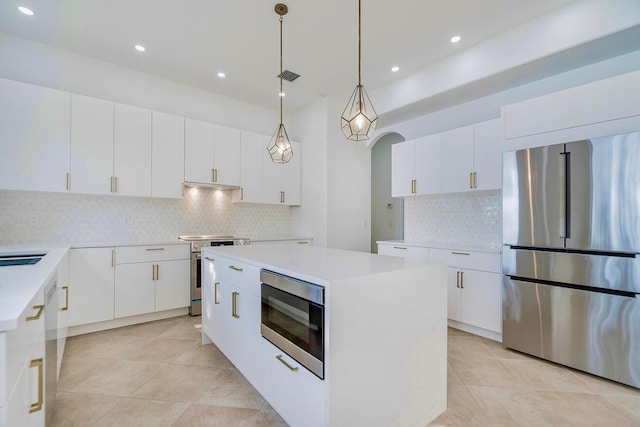 kitchen featuring a kitchen island, hanging light fixtures, stainless steel appliances, tasteful backsplash, and white cabinetry