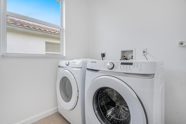 washroom featuring plenty of natural light, washer hookup, washing machine and clothes dryer, and light tile floors