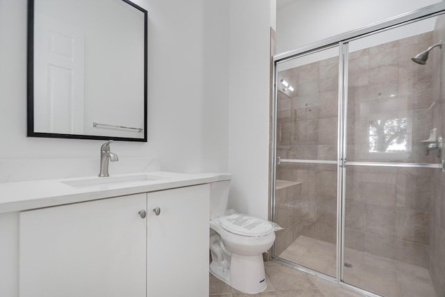 bathroom with vanity, tile floors, a shower with shower door, and toilet