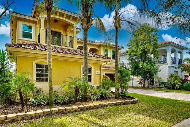 mediterranean / spanish-style home with a balcony and a front lawn