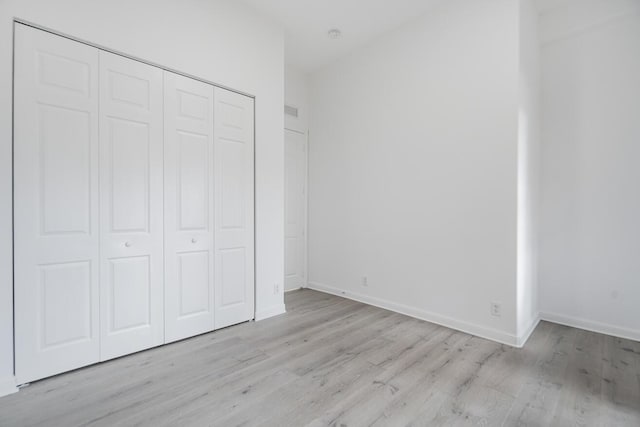 unfurnished bedroom with a closet and light hardwood / wood-style floors