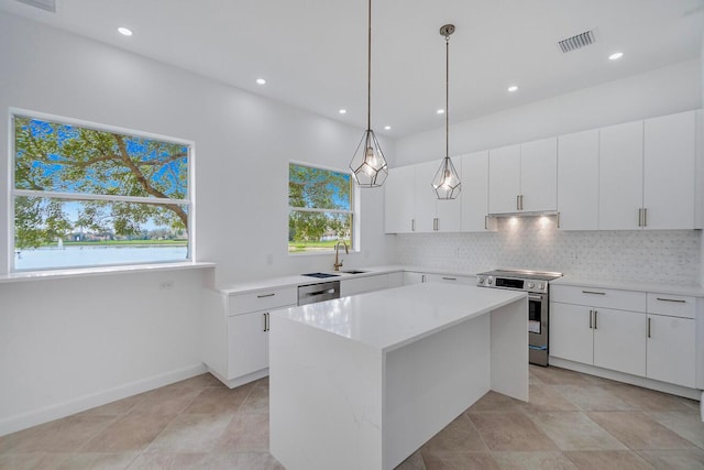 kitchen featuring appliances with stainless steel finishes, white cabinetry, decorative light fixtures, and a center island