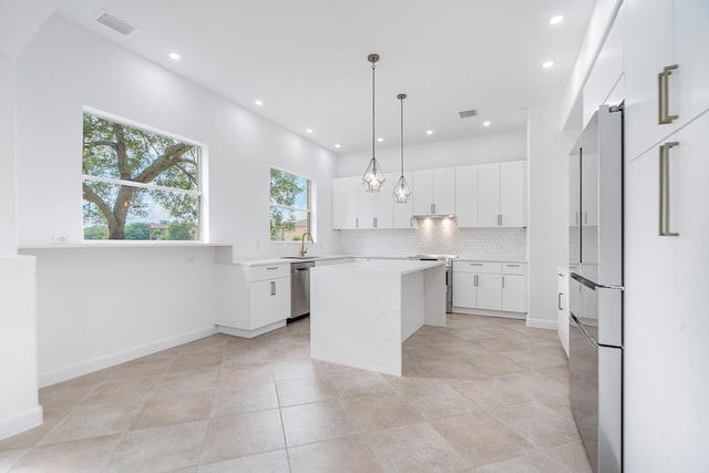 kitchen with pendant lighting, a kitchen island, stainless steel appliances, and white cabinetry