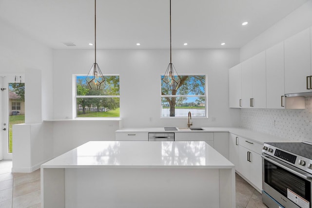 kitchen featuring light tile floors, appliances with stainless steel finishes, white cabinetry, and a center island