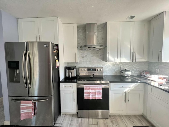 kitchen with wall chimney exhaust hood, white cabinetry, stainless steel appliances, and tasteful backsplash