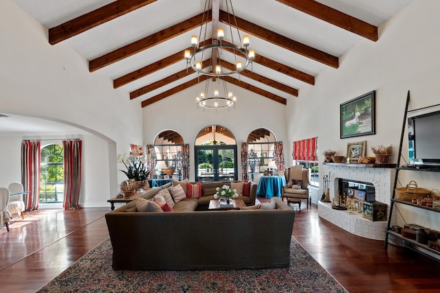 living room with dark hardwood / wood-style floors, a brick fireplace, beam ceiling, high vaulted ceiling, and an inviting chandelier