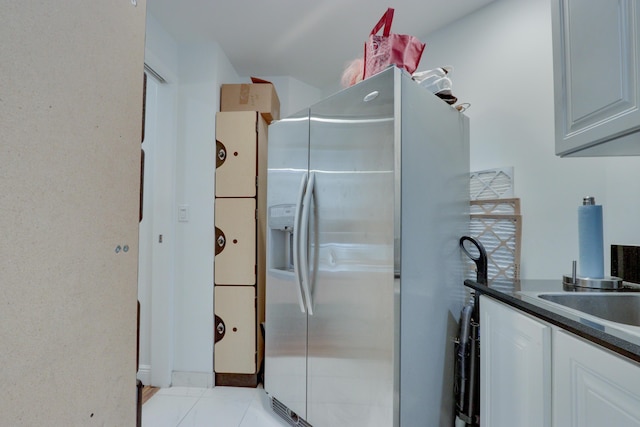 kitchen with stainless steel fridge with ice dispenser, white cabinetry, and light tile flooring