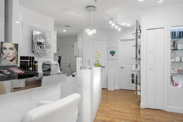 interior space featuring track lighting, white cabinets, pendant lighting, and light wood-type flooring