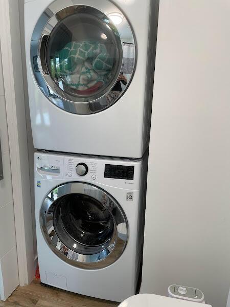 washroom with stacked washing maching and dryer and hardwood / wood-style flooring