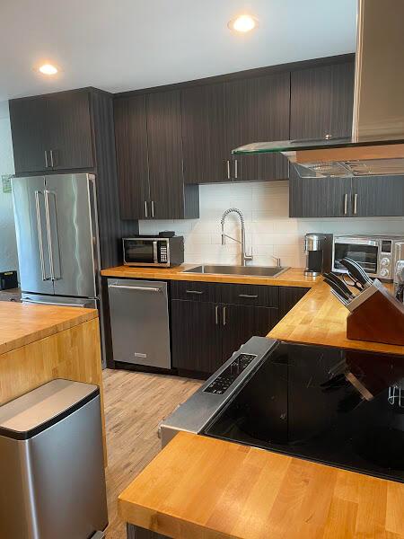 kitchen featuring butcher block countertops, appliances with stainless steel finishes, sink, light wood-type flooring, and tasteful backsplash