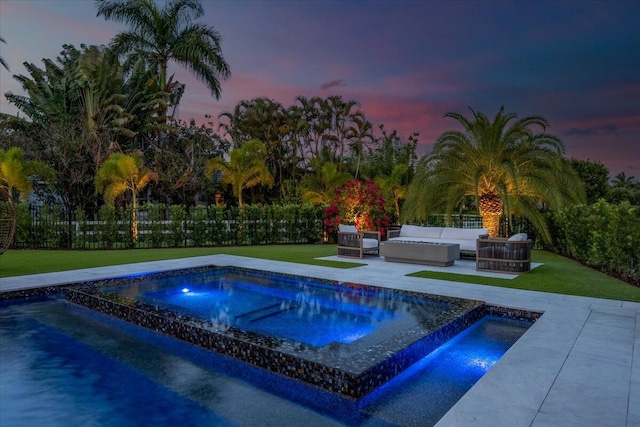 pool at dusk featuring a lawn, outdoor lounge area, and a patio