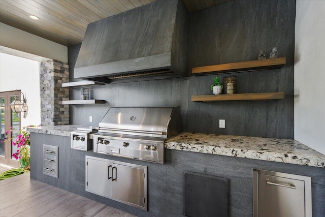 kitchen with hardwood / wood-style floors, custom range hood, and light stone counters