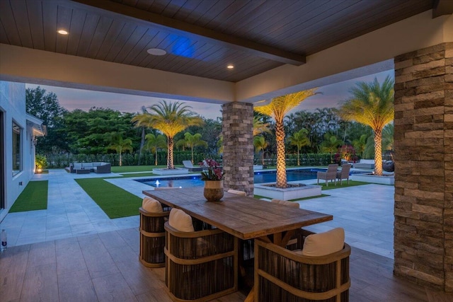 patio terrace at dusk featuring a swimming pool with hot tub