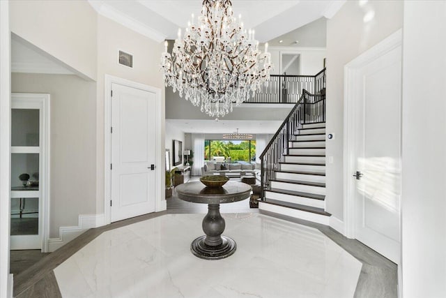 foyer featuring crown molding, a high ceiling, and an inviting chandelier