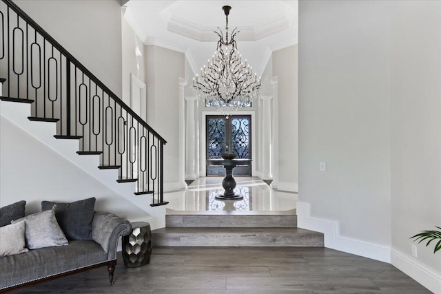 entrance foyer featuring dark hardwood / wood-style floors, french doors, ornamental molding, a high ceiling, and an inviting chandelier