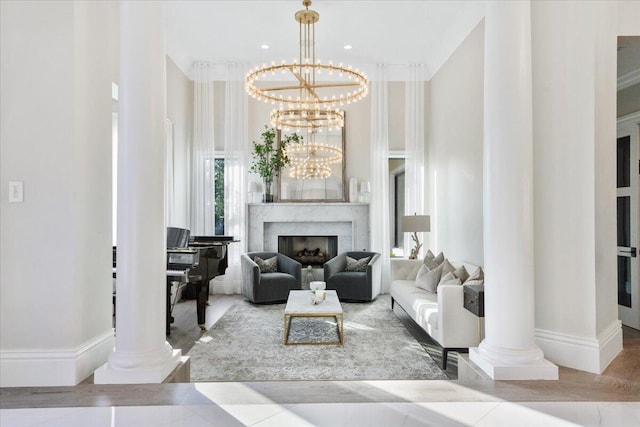 living room featuring a notable chandelier, ornate columns, a towering ceiling, and ornamental molding