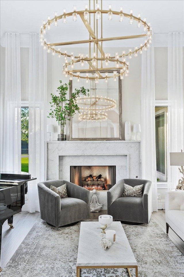 living room featuring a notable chandelier, a high end fireplace, and light wood-type flooring