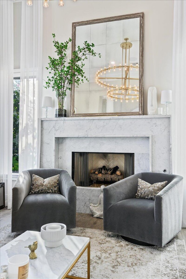 living area featuring a notable chandelier, light hardwood / wood-style floors, a wealth of natural light, and a fireplace