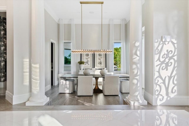 dining space featuring a high ceiling, ornamental molding, dark wood-type flooring, and ornate columns