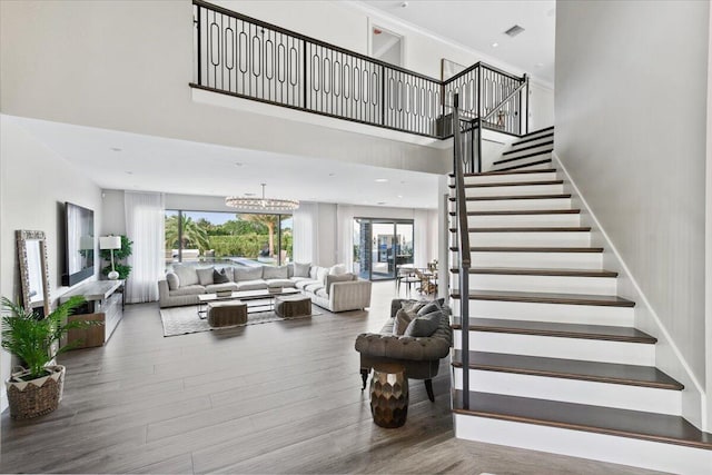 stairway with a chandelier, wood-type flooring, and a towering ceiling