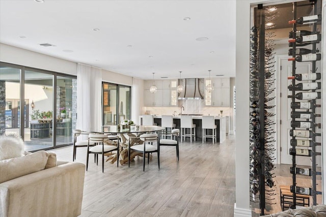 wine room with a notable chandelier, light wood-type flooring, and sink