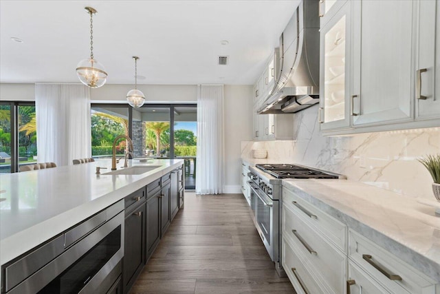 kitchen featuring wall chimney range hood, tasteful backsplash, appliances with stainless steel finishes, white cabinetry, and dark hardwood / wood-style flooring