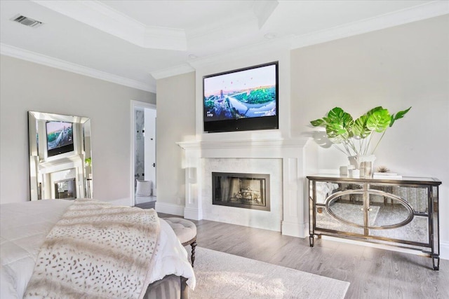 bedroom with light hardwood / wood-style floors, ornamental molding, and a tray ceiling