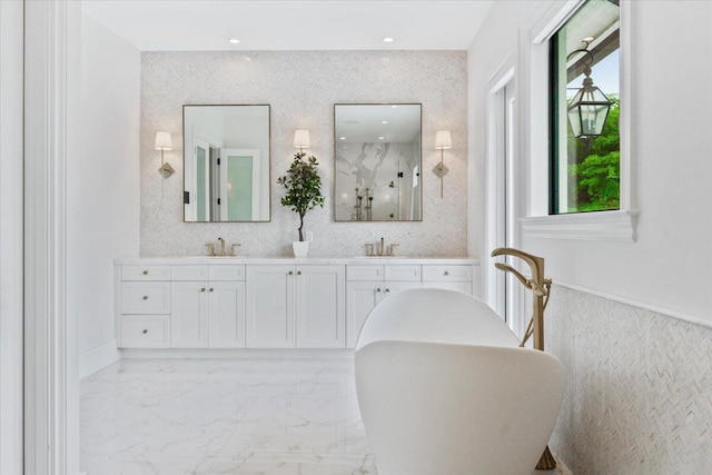 bathroom with a bathing tub, oversized vanity, and dual sinks