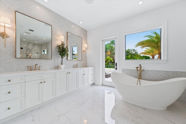 bathroom featuring dual vanity, tile flooring, a tub, and tile walls