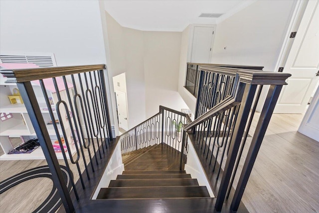 stairway featuring a high ceiling and light hardwood / wood-style floors