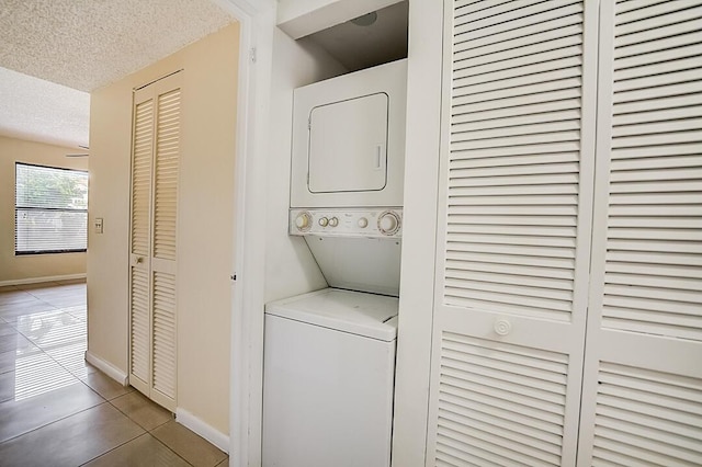 clothes washing area featuring light tile floors, a textured ceiling, and stacked washer / drying machine