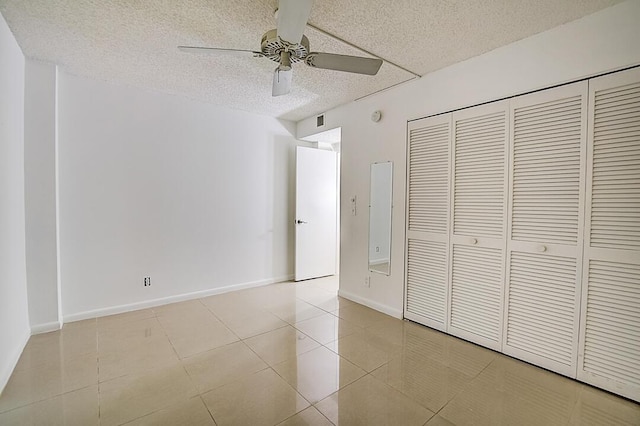 unfurnished bedroom with light tile flooring, a closet, ceiling fan, and a textured ceiling