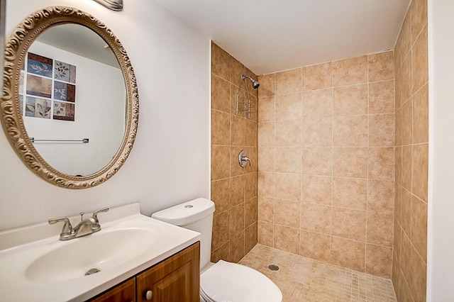 bathroom featuring toilet, vanity, and tiled shower