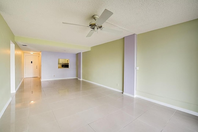 empty room with light tile flooring, ceiling fan, and a textured ceiling