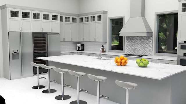 kitchen with a kitchen bar, tasteful backsplash, sink, and premium range hood