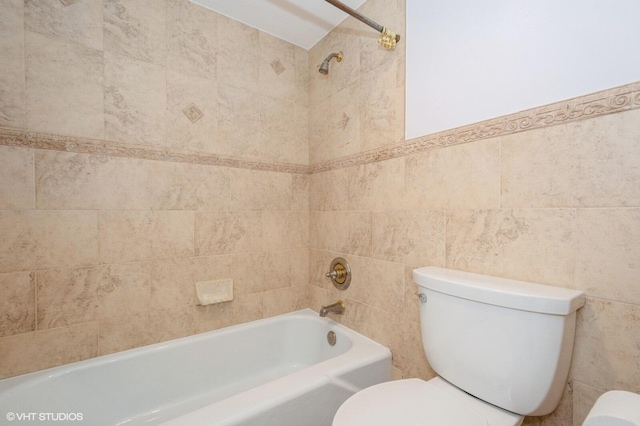 bathroom with tiled shower / bath, tile walls, and toilet