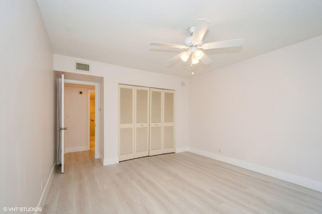 unfurnished bedroom featuring light wood-type flooring, a textured ceiling, ceiling fan, and a closet