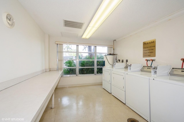 washroom with ornamental molding, washer and dryer, and a textured ceiling