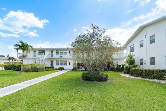 view of front facade with a balcony and a front yard