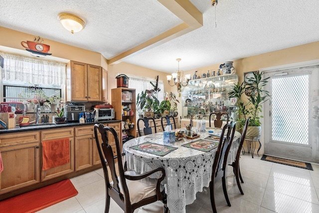 tiled dining space featuring an inviting chandelier, a textured ceiling, and sink