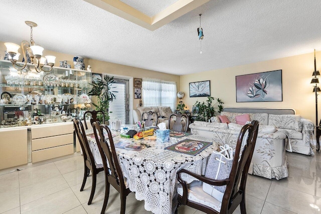 tiled dining room with an inviting chandelier and a textured ceiling