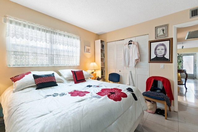 bedroom featuring light tile floors, a textured ceiling, and a closet