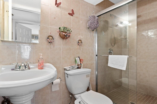 bathroom with a shower with door, tasteful backsplash, toilet, and tile walls